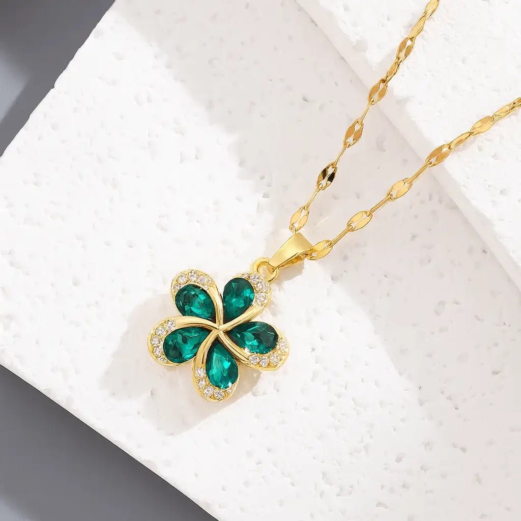 Gold necklace with a green four-leaf clover pendant on a white background